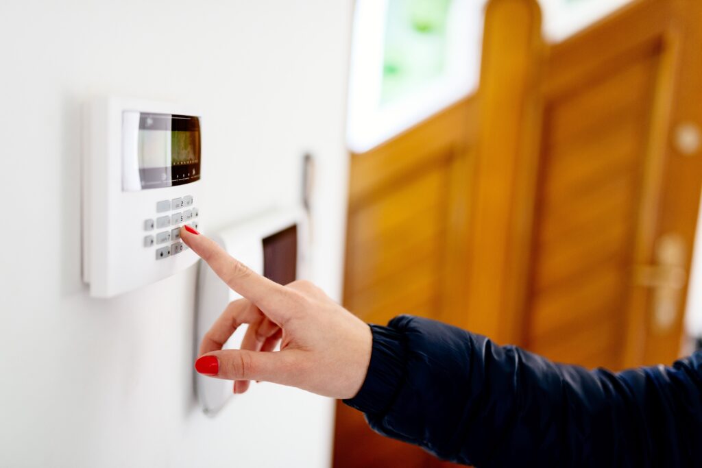 Young woman entering security code on home security alarm system keypad
