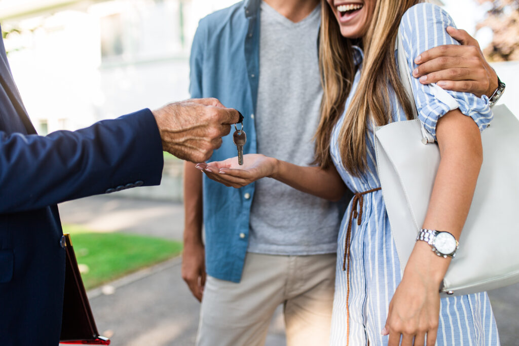 Young happy couple talking with real estate agent and buying a new house.
