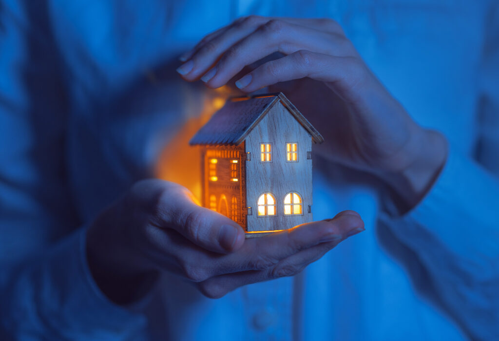 Person Holding a Wooden House Model